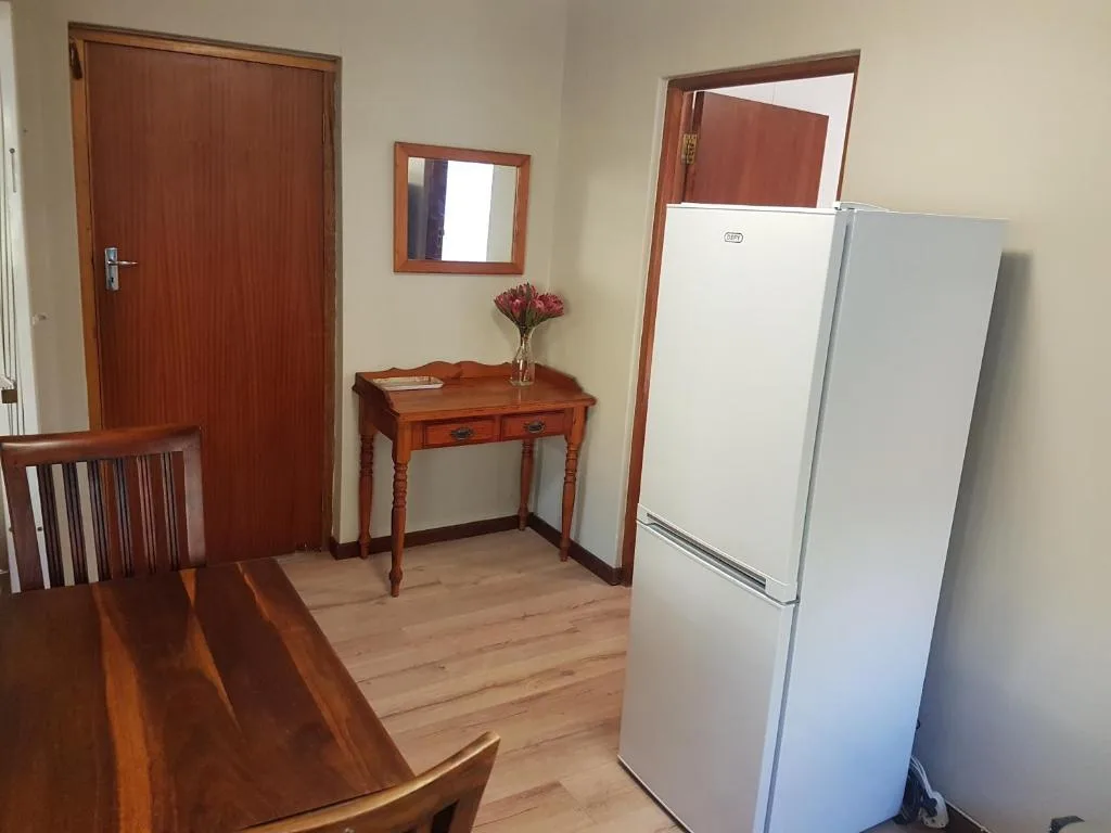 Kitchen area with white refrigerator, wooden table, and red door entrance
