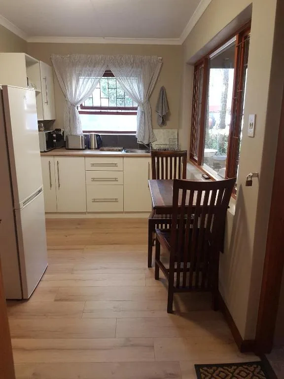 Modern kitchen with cream cabinetry, refrigerator, and dining area visible