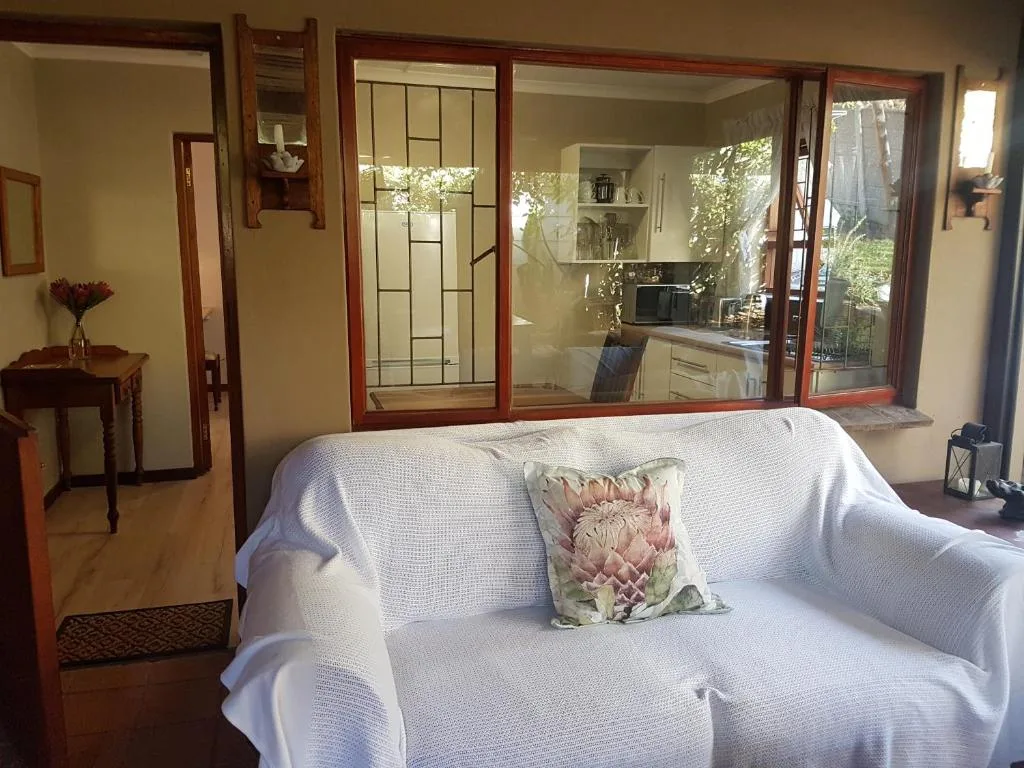 Bright lounge with white sofa, kitchen view through glass doors, natural light