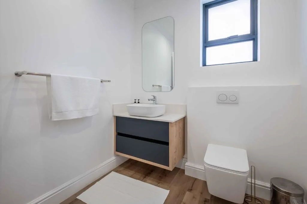 Modern bathroom with round mirror, wall-mounted sink vanity, and toilet