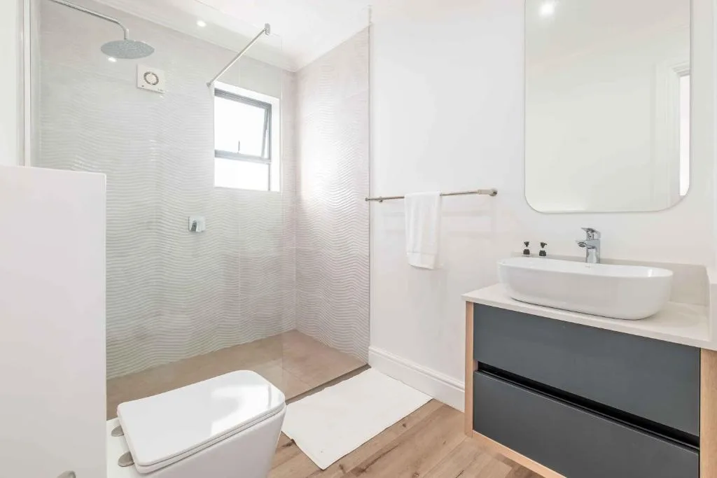 Modern bathroom with rainfall showerhead, vessel sink, and white tiling