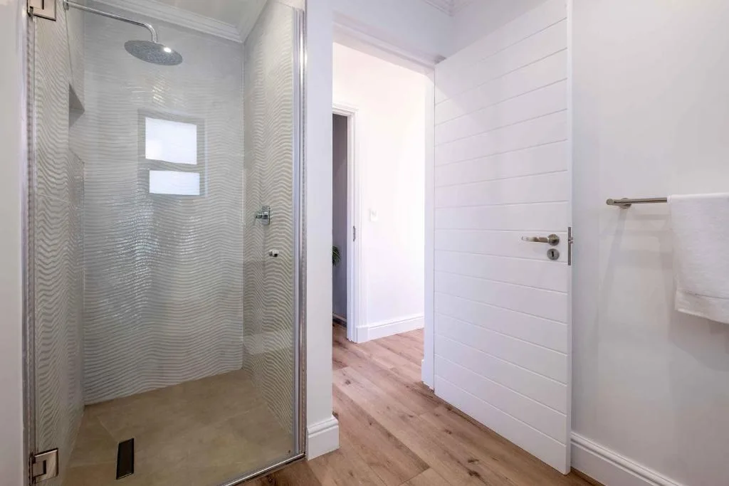 Modern bathroom with walk-in shower, white subway tile, and wooden flooring
