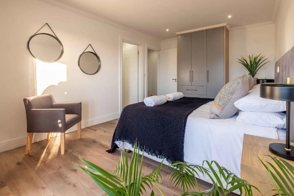 Bright modern bedroom with queen bed, grey wardrobe, and sitting chair