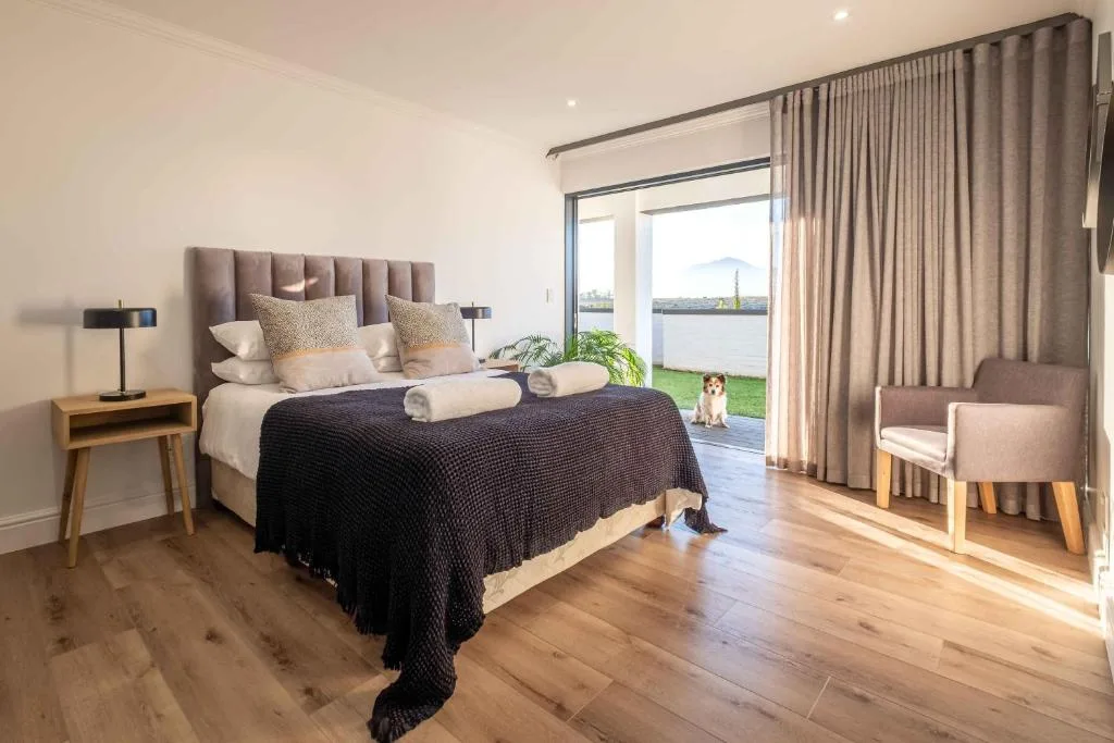Spacious bedroom with upholstered headboard overlooking lagoon views through glass doors