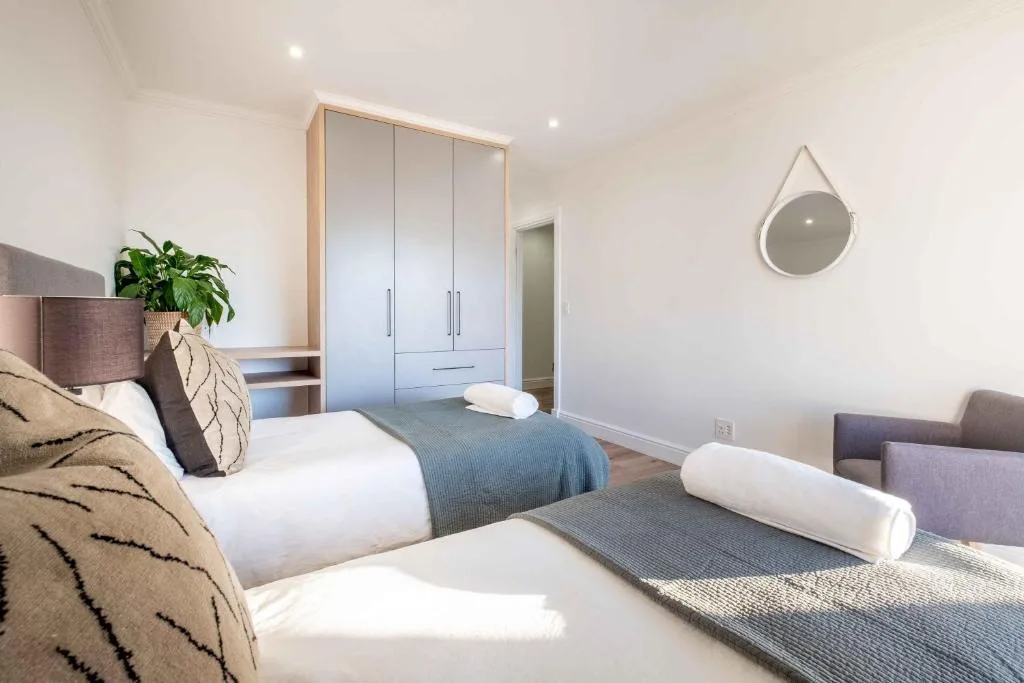 Bright modern bedroom with two beds, built-in wardrobes, and contemporary decor