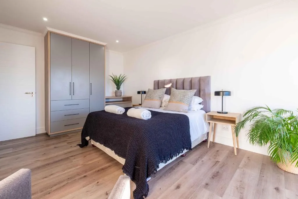 Modern bedroom with queen bed, grey headboard, wooden nightstands, and built-in wardrobe