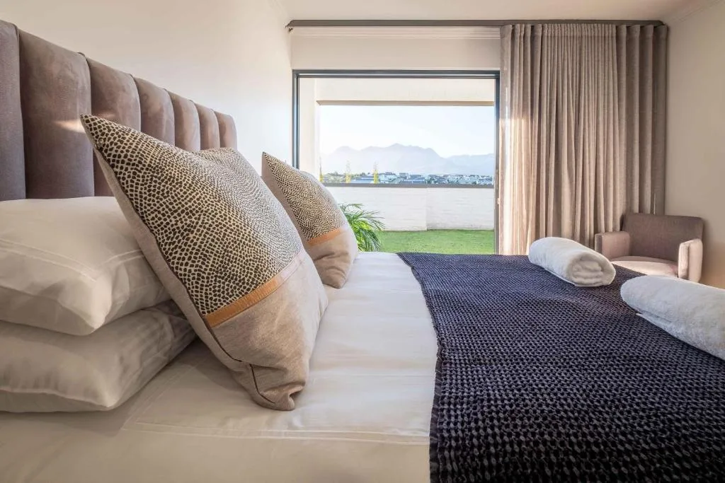 Modern bedroom with waterfront view through sliding glass doors and mountains beyond