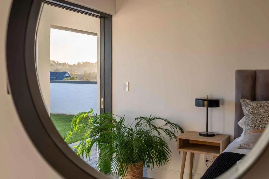 Modern bedroom with sliding glass door opening to lagoon view and grounds