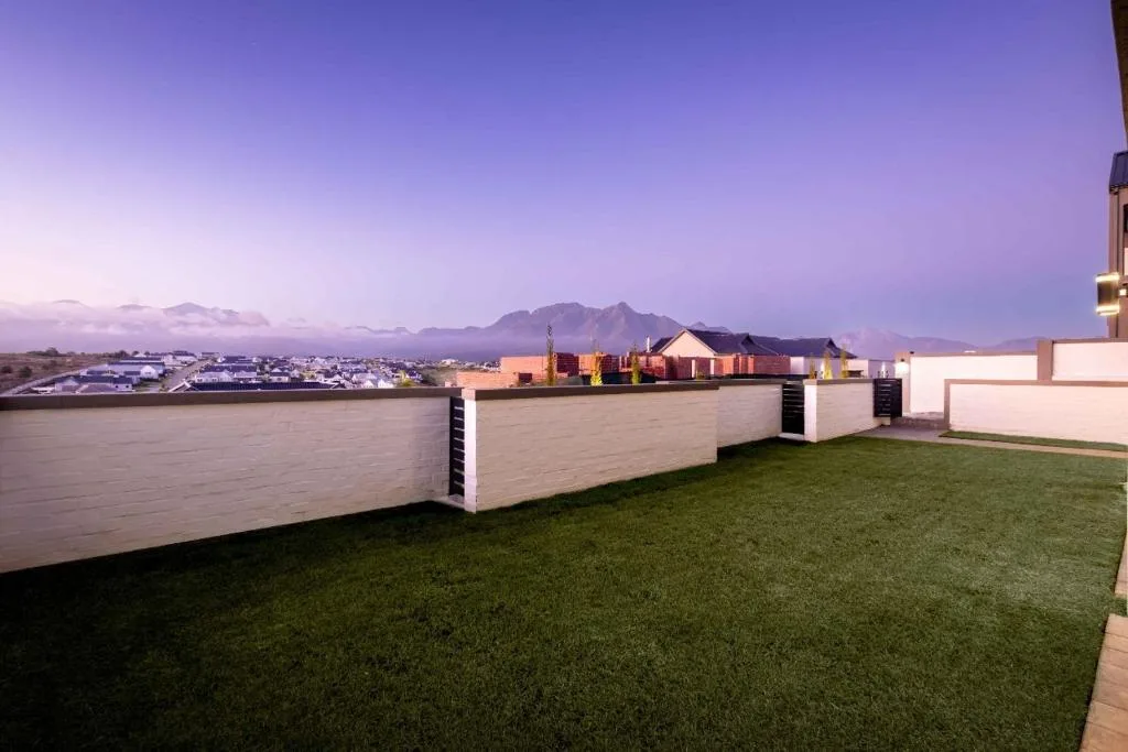 Rooftop terrace with manicured lawn overlooking George town and mountains at dusk