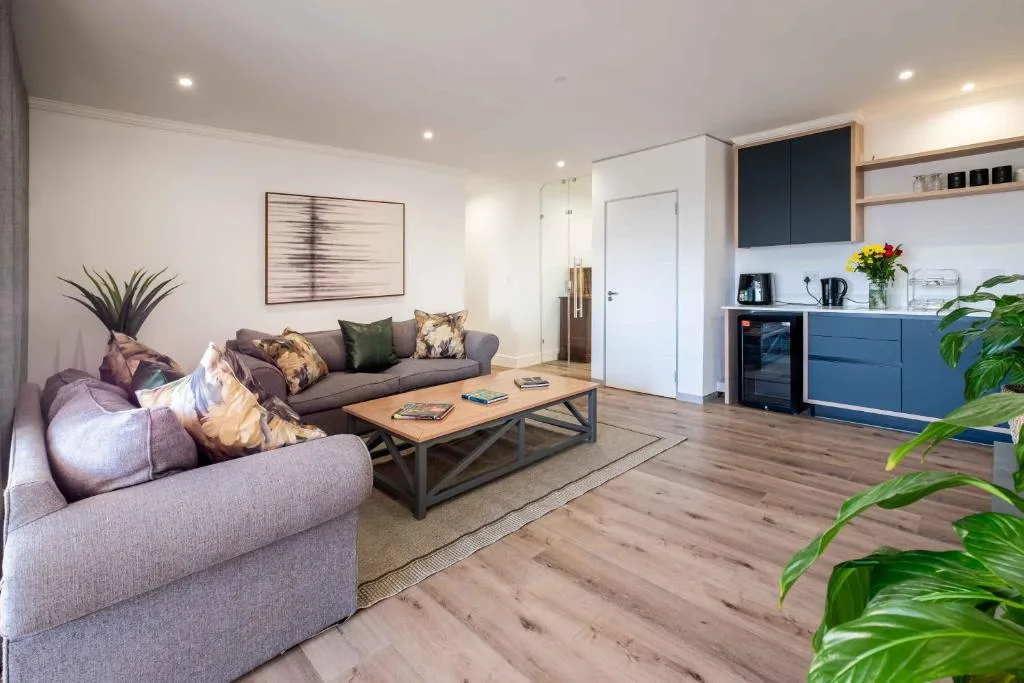 Modern lounge with gray sofa, wooden coffee table, and kitchenette