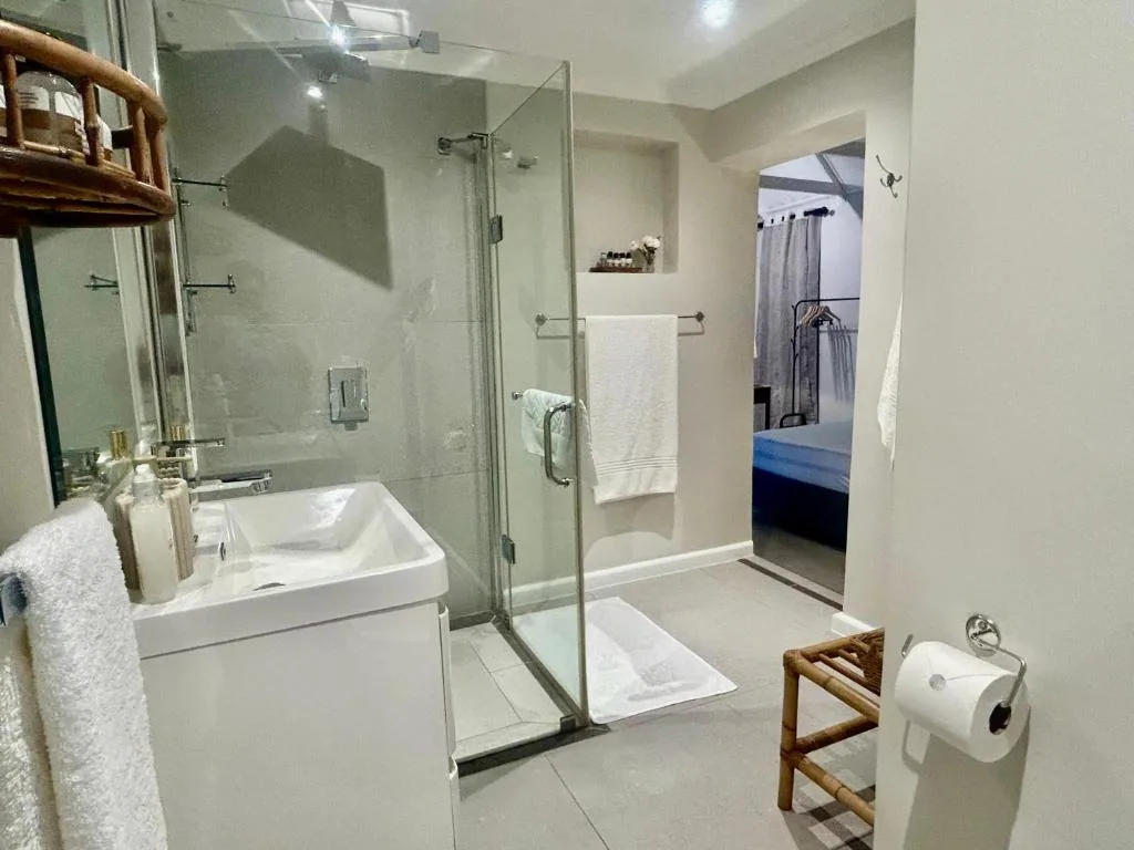 Modern bathroom with walk-in shower, white vanity, and glass enclosure
