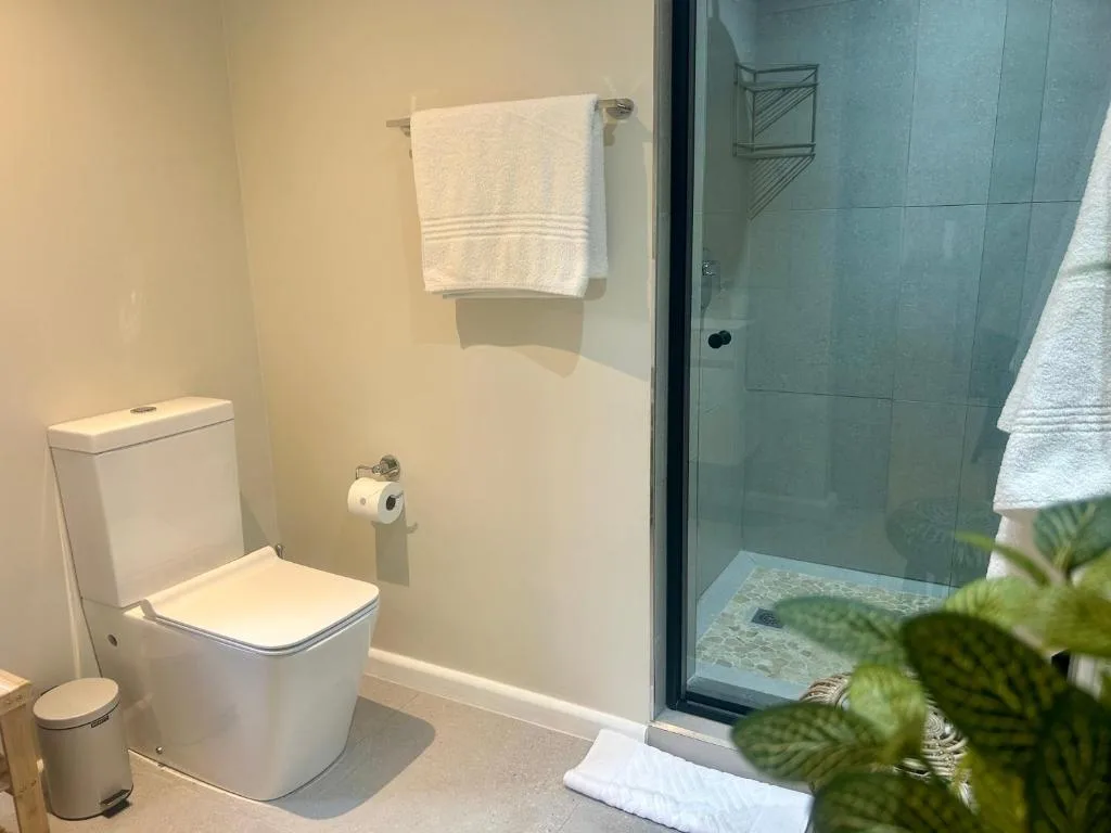 Modern bathroom with toilet, shower enclosure, and towel rack