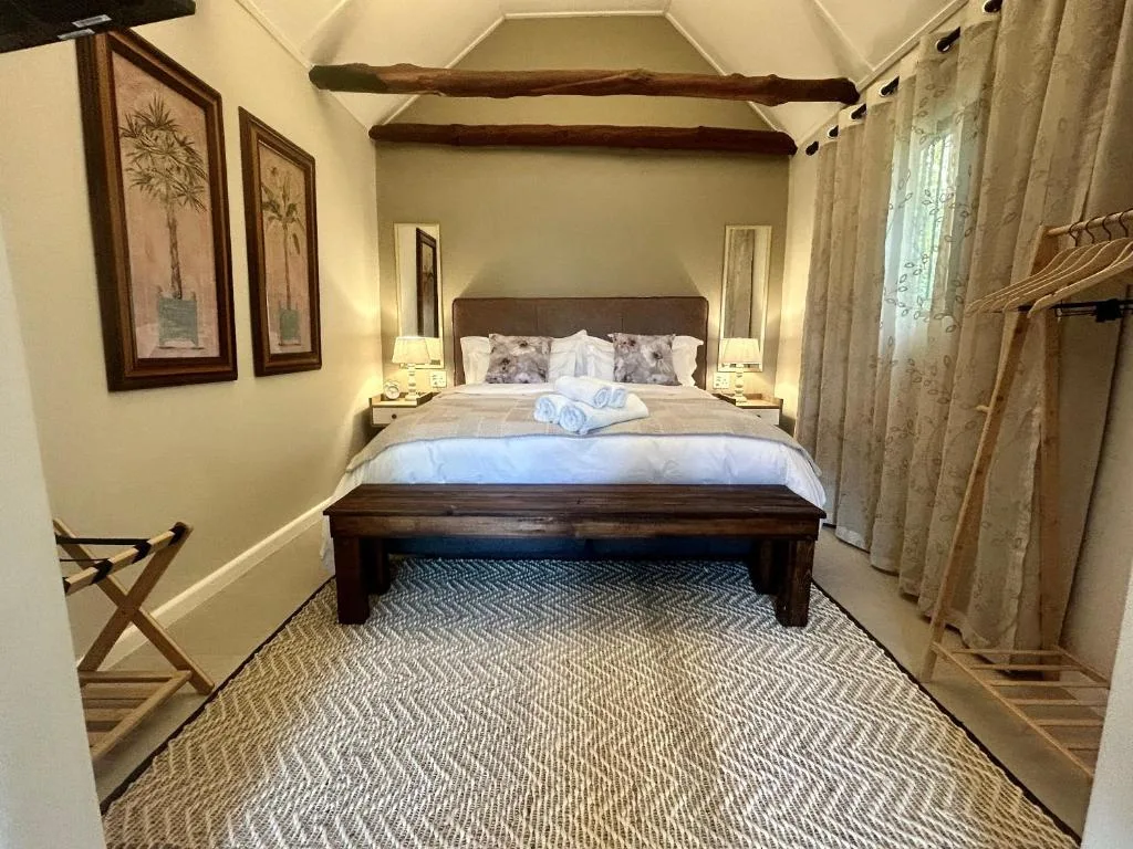 Spacious bedroom with king bed, dark wooden furniture, and exposed beams