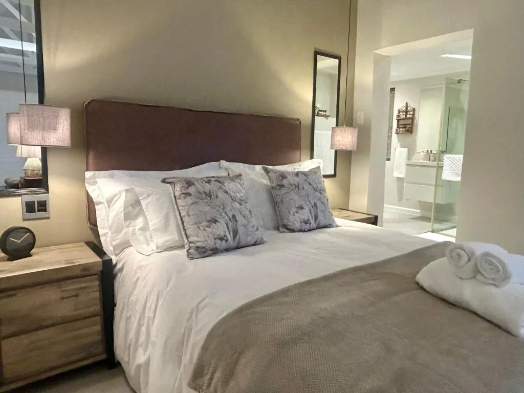 Modern bedroom with queen bed, brown leather headboard, ensuite bathroom visible