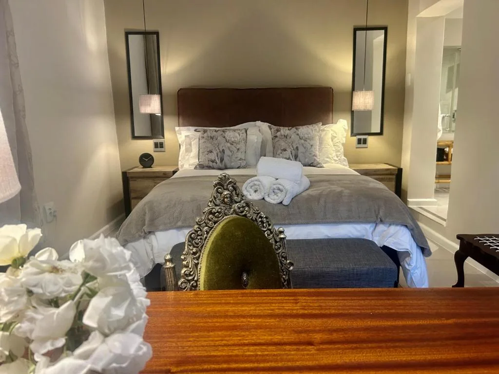 Master bedroom with brown headboard, crisp linens, and modern sconces