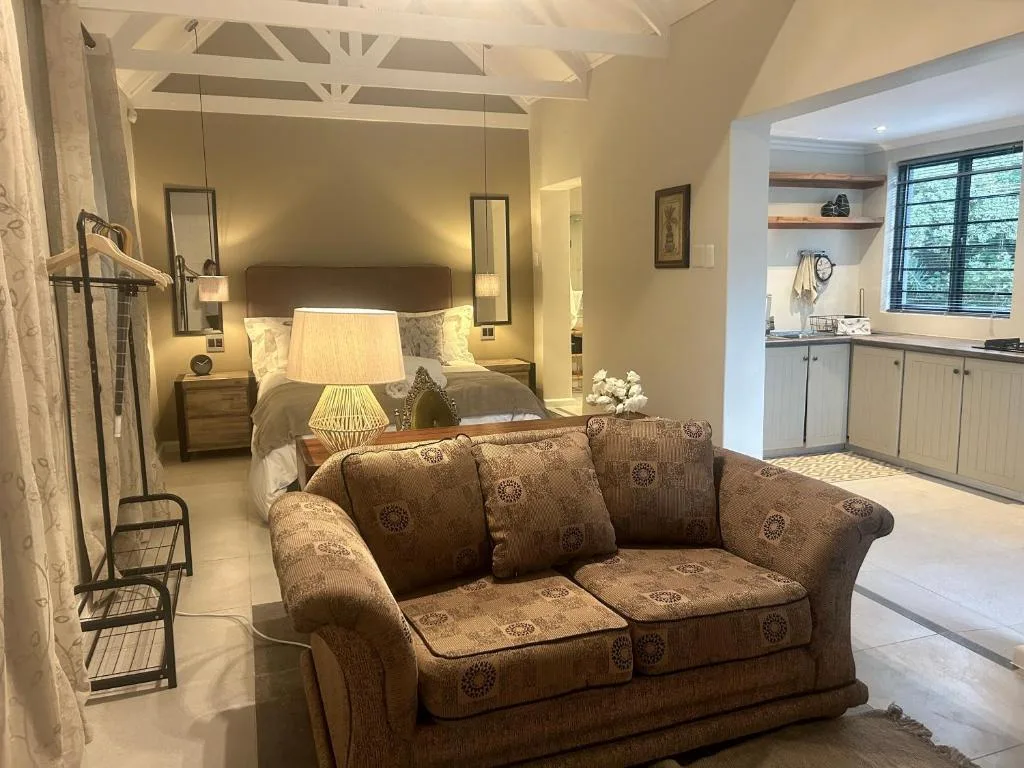 Spacious bedroom with upholstered sofa, bed, nightstands, and ensuite bathroom visible