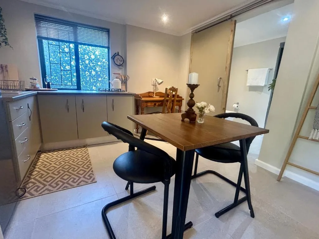 Modern dining table with black chairs and kitchen area visible in background