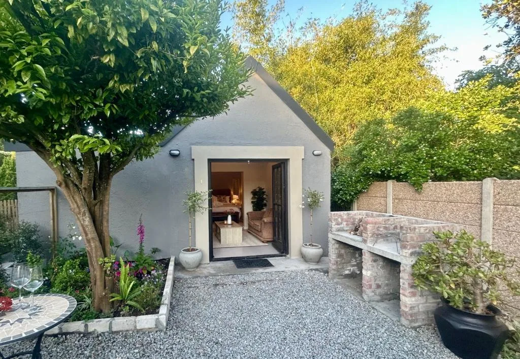 Modern white cottage entrance with landscaped garden and brick wall