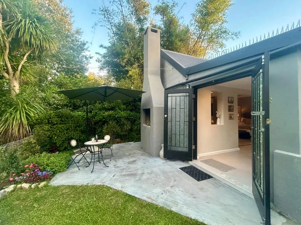Modern cottage entrance with patio, garden seating, and lush landscaping