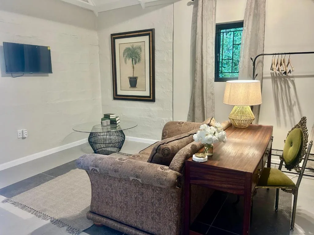 Open-plan lounge with comfortable seating, wooden dining table, and wall-mounted television.