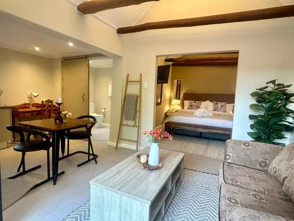 Open-plan lounge with sofa, dining table, and bedroom view beyond