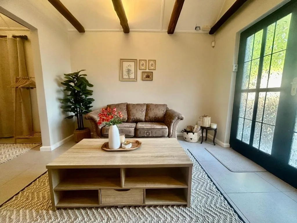 Bright living room with beige sofa, wooden beams, and garden views through doors