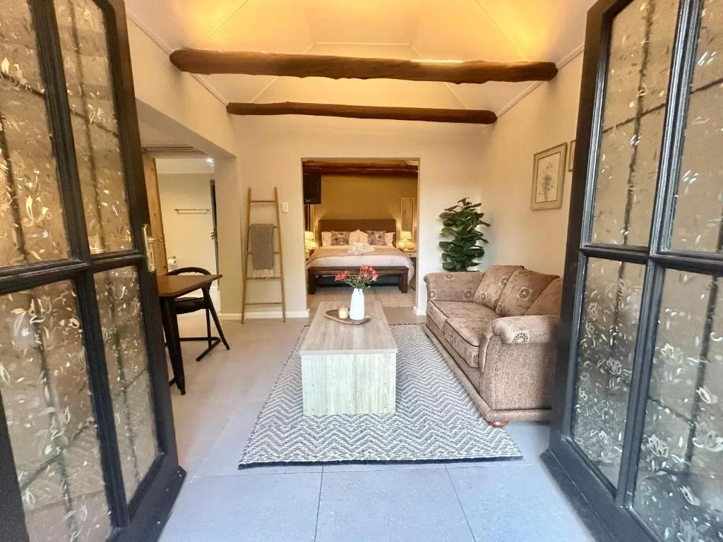 Open-plan lounge with sofa, coffee table, and bedroom view beyond