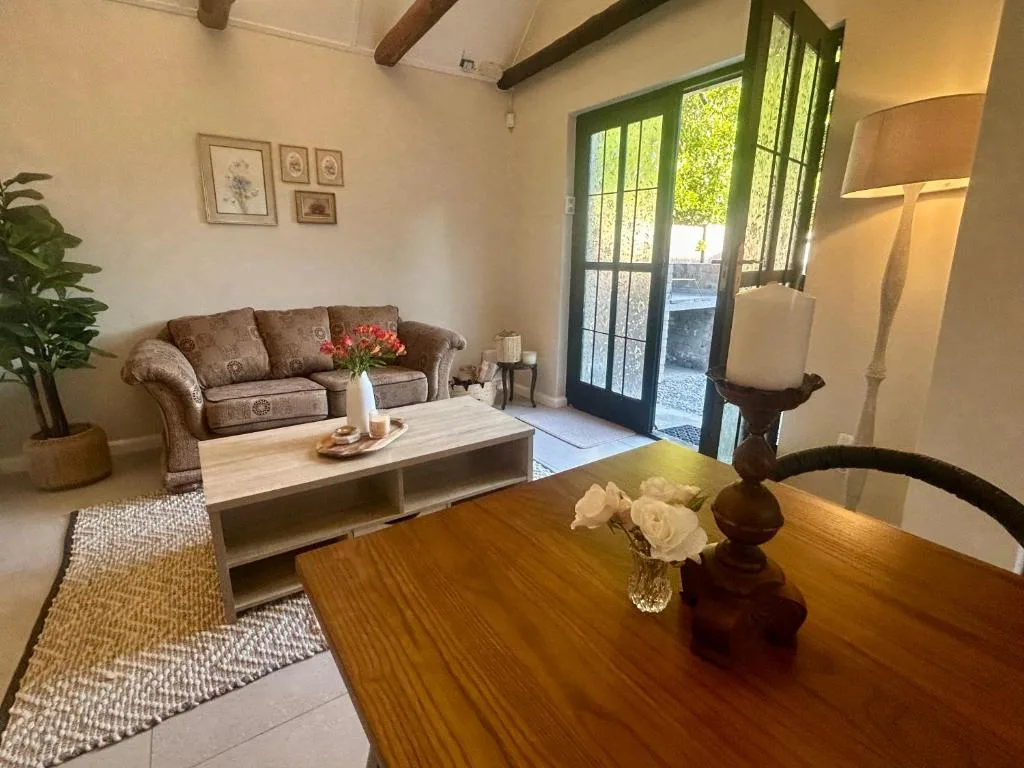 Spacious lounge with brown sofa, wooden dining table, and garden view doors