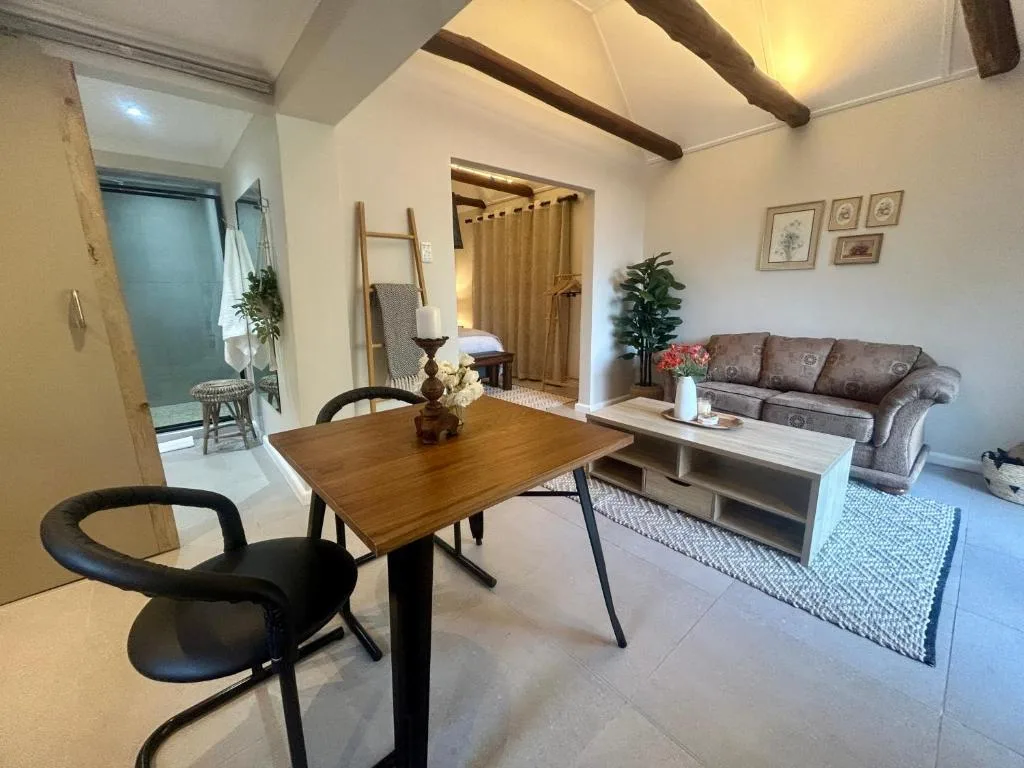 Open-plan living area with sofa, dining table, and exposed wooden beams