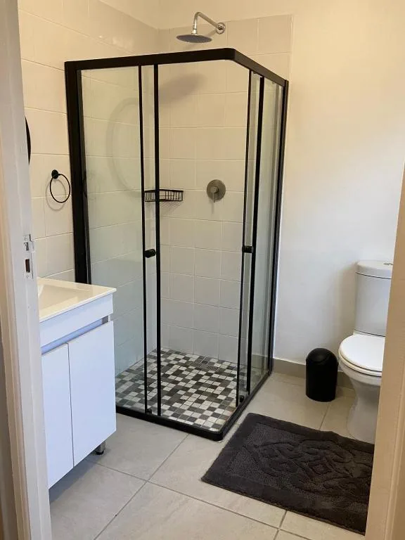 Modern bathroom with black-framed shower enclosure and white vanity