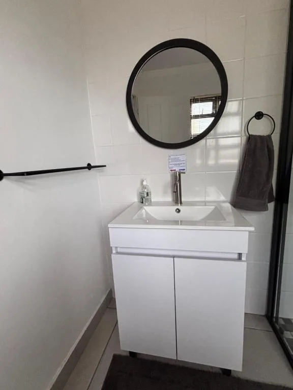 Modern bathroom vanity with white sink cabinet and round black mirror