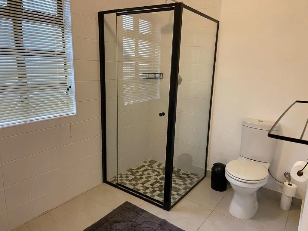 Modern bathroom with black-framed shower enclosure and white toilet