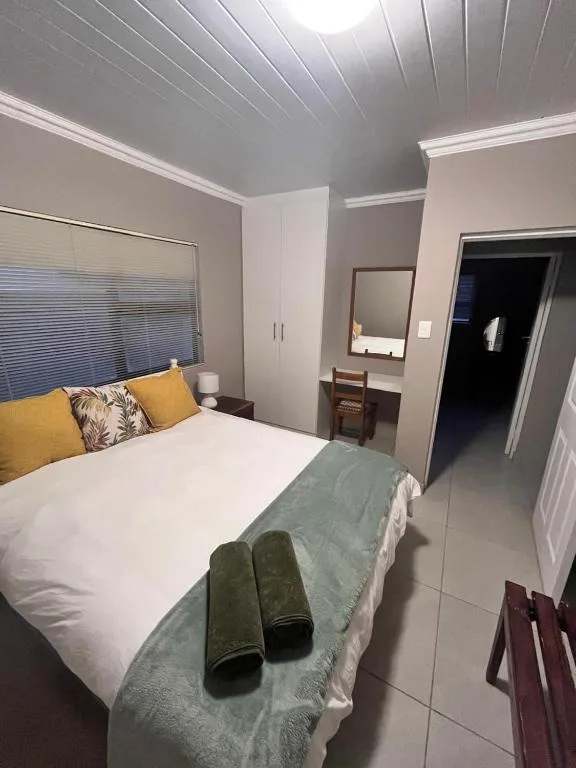 Neat bedroom with queen bed, yellow pillows, built-in wardrobe, vanity mirror
