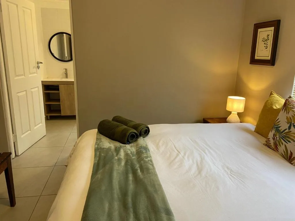 Spacious bedroom with queen bed, ensuite bathroom, warm lighting, and modern decor
