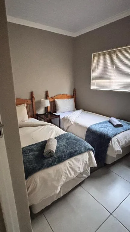 Twin bedroom with wooden headboards and white bedding, bright window