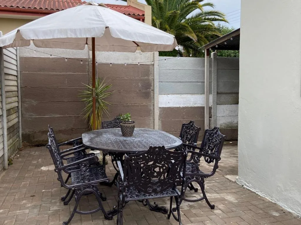 Outdoor patio with round dining table, black chairs, and white umbrellas
