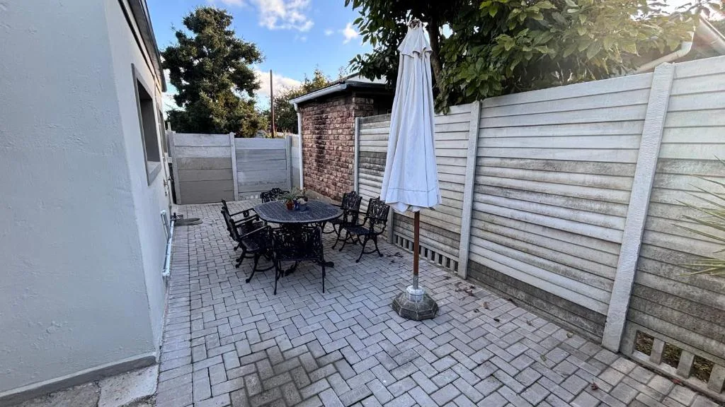 Paved patio with dining table, umbrella, and privacy fencing