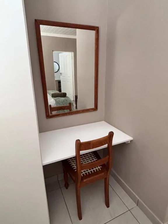 Wooden framed mirror above white desk with chair in bedroom alcove