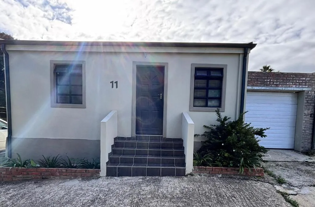 White cottage front facade with dark door, windows, and numbered entrance eleven