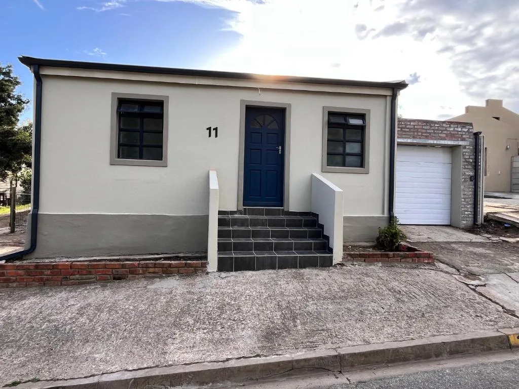 Modern cream cottage with navy door and dark windows, numbered 11