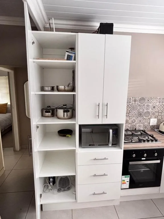 White kitchen cabinetry with open shelving displaying cookware and appliances