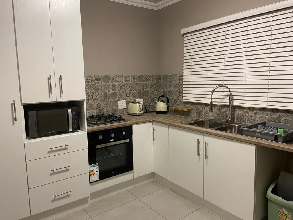 Modern white kitchen with black oven, stainless sink, and patterned backtile