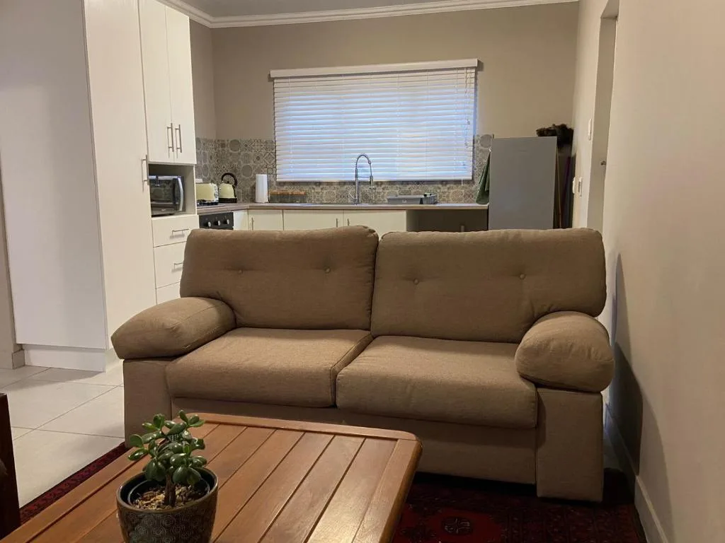 Beige sofa with cushioned armrests in open-plan living area with kitchen visible
