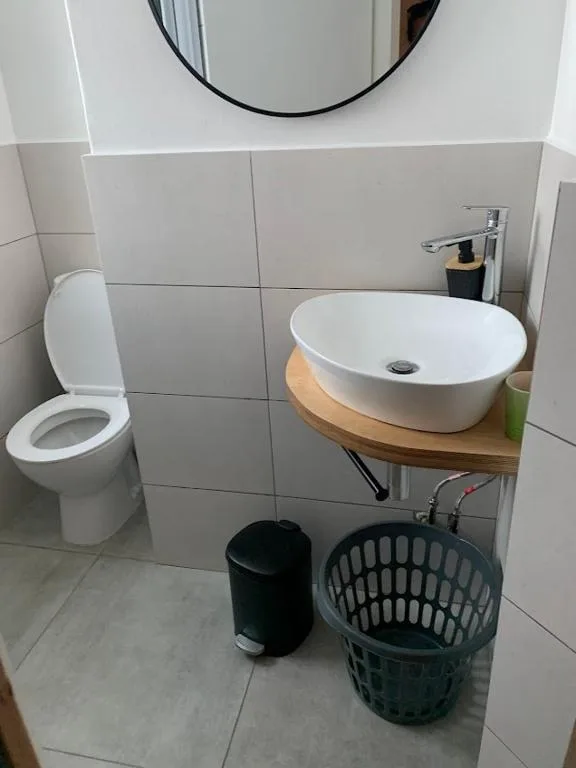Modern bathroom with white vessel sink, toilet, and tiled walls