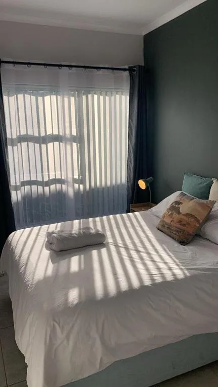 Bright bedroom with white bedding and dark green accent wall