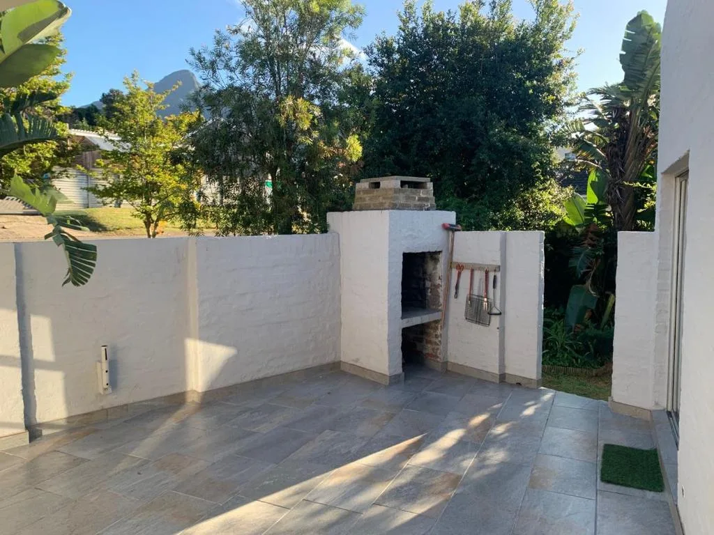 Paved outdoor patio with built-in braai area and white boundary walls