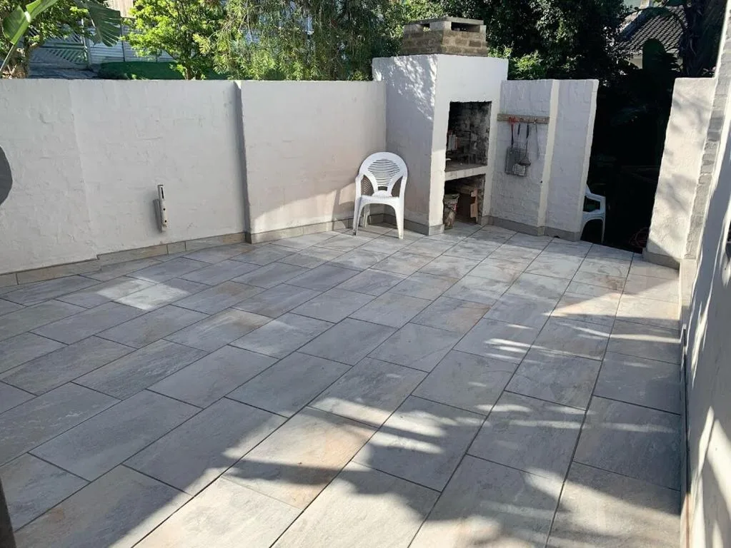 Spacious paved patio with white walls and mature tree shade