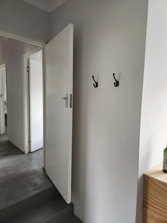 Modern hallway with white doors and black wall hooks for coats