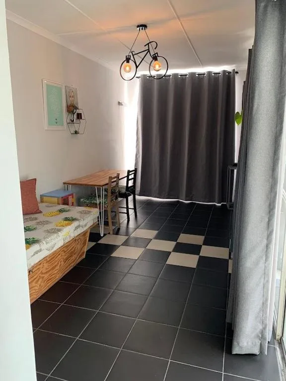 Dining area with wooden table, black and beige tile flooring, bicycle pendant light