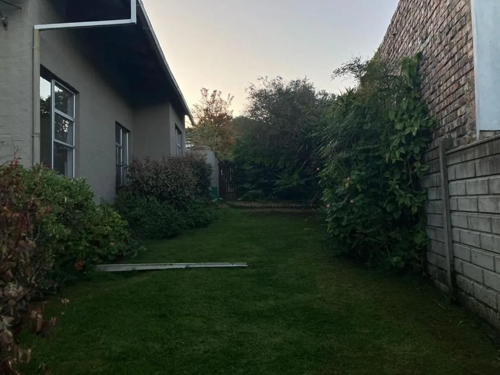 Modern white cottage with manicured garden and brick boundary walls